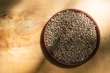 Hemp seeds in a clay dish. Wood background