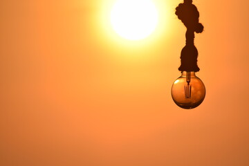 Hanging filament light bulb in a golden sunset