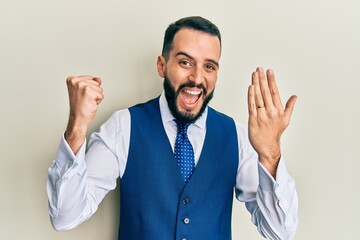 Young man with beard wearing engagement ring screaming proud, celebrating victory and success very excited with raised arms