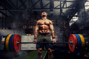 Fototapeta na wymiar Weightlifter in the gym, visual effects of positive energy on training. Strong attractive man holds a heavy barbell in his hands and lifts a weight in a modern gym concept. Screaming during exercises