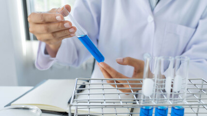 scientists researching in laboratory in white lab coat, gloves analysing, looking at test tubes sample, biotechnology concept