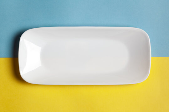Close-up of an empty ceramic white rectangular or rectangle tray plate for mockup. Over yellow blue background