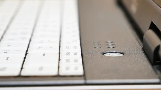 Man pressing a power button on a laptop, finger extreme closeup, object detail. Turning on, powering on a notebook, computer, electronic device abstract concept. Booting up a laptop, object up close