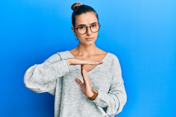 Young hispanic woman wearing casual clothes doing time out gesture with hands, frustrated and...