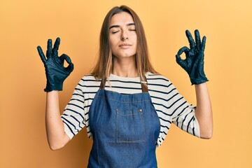 Young hispanic woman wearing barber apron relax and smiling with eyes closed doing meditation gesture with fingers. yoga concept.
