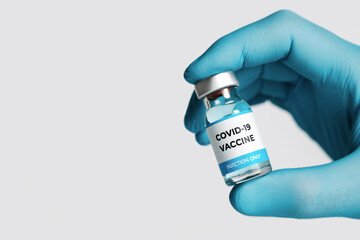 Close up of Covid-19 vaccineon white background. Hand with blue medical gloves takes one bottle of...
