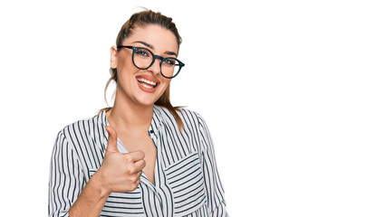 Young caucasian woman wearing business shirt and glasses doing happy thumbs up gesture with hand....