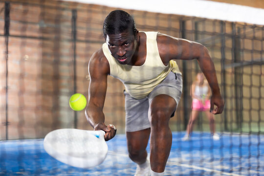 African american man playing paddle tennis indoors