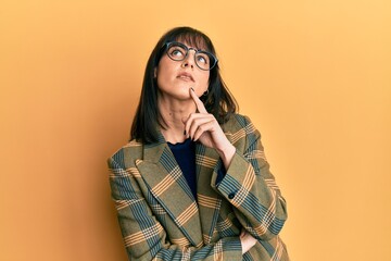 Young hispanic woman wearing business style and glasses thinking concentrated about doubt with...
