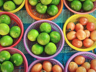 High Angle View of Fresh Lime Fruits and Small Tomatoes in Plastic Baskets