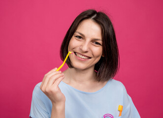 Beautiful happy young woman with single tufted toothbrush on blank pink background