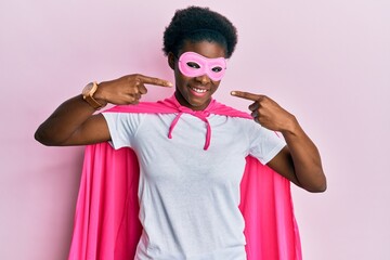 Young african american girl wearing superhero mask and cape costume smiling cheerful showing and...