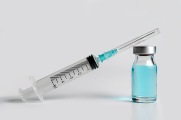 Close up of Covid-19 vaccine blue bottle and syringe on white background. Medical coronavirus vaccination concept.