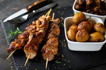 Fried meat on a skewer with baked potatoes and mushrooms