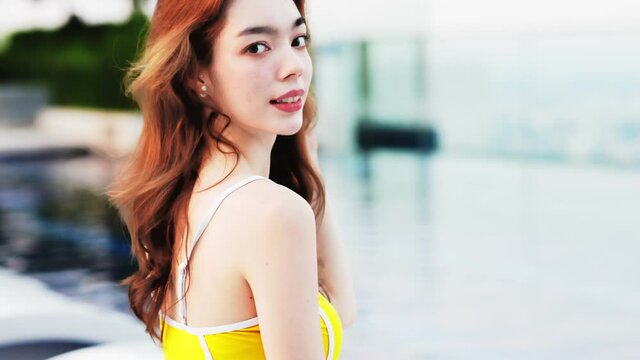 Asian young woman relax in swimming pool at luxury hotel spa enjoying beautiful .Close up Female Enjoying Summer Travel in City Hotel. vacation woman .