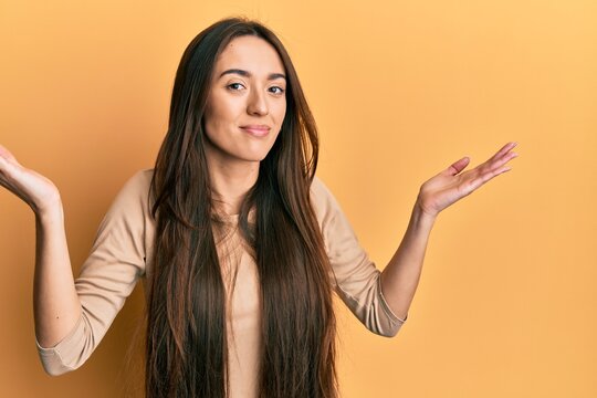 Young hispanic girl wearing casual clothes clueless and confused with open arms, no idea and doubtful face.