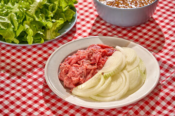 Summer party menu with beef, shrimp, roasted duck, fresh vegetable and sea grapes on red white caro background