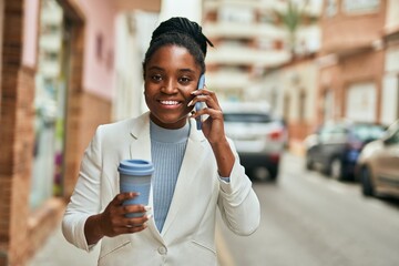 Young african american businesswoman talking on the smartphone and drinking coffee at the city.
