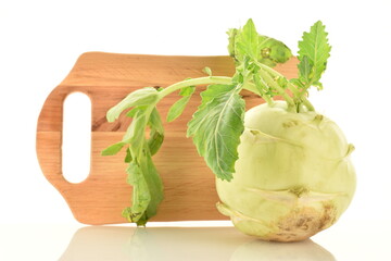 One uncooked organic kohlrabi cabbage with cutting wooden board, close-up, isolated on white.