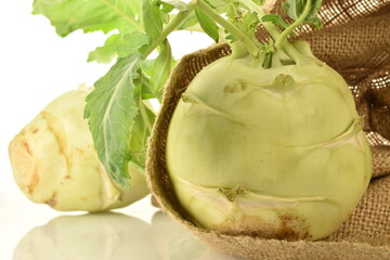 Two uncooked organic kohlrabi cabbage with jute bag, close-up, isolated on white.