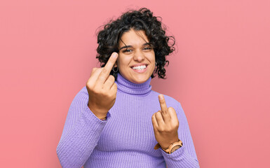 Young hispanic woman with curly hair wearing casual clothes showing middle finger doing fuck you...
