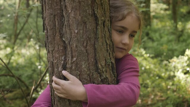 Contented Little Girl Hugging Large Tree With Blissful Expression of Nature Conservation. Harmony Calm Relaxation. Save Earth Green Planet. Child Girl Hugging Tree Trunk in Park, Nature Life Love.