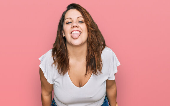 Young plus size woman wearing casual white t shirt sticking tongue out happy with funny expression. emotion concept.