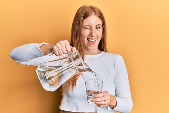 Young Irish Woman Pouring Water Winking Looking At The Camera With Sexy Expression, Cheerful And Happy Face.