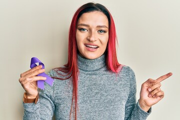 Young caucasian woman holding purple ribbon awareness smiling happy pointing with hand and finger...