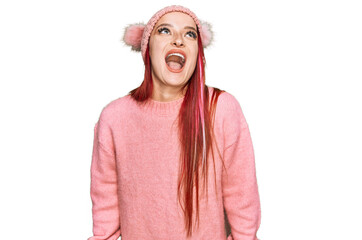 Young caucasian woman wearing casual clothes and wool cap angry and mad screaming frustrated and...