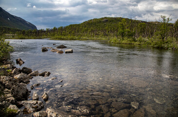 Northern Sweden. Rocky mountain river against the backdrop of sparse vegetation and cloudy sky