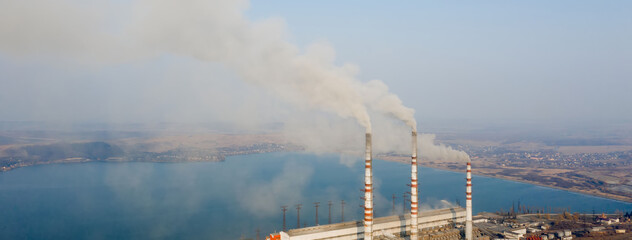 Aerial view of high chimney pipes with grey smoke from coal power plant. Production of electricity with fossil fuel. © volody10