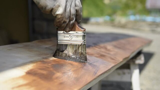 Painting a wooden surface with varnish and brush, impregnation of wood, dark paint color