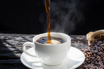The steam from Pouring coffee into cup , A cup of fresh coffee on old kitchen table. with copy space. A scattering of coffee beans with a cup of coffee. Coarse fabric.hot food and healthy meal concept