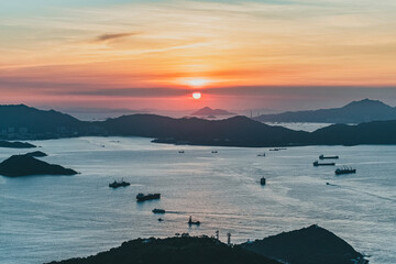 Stunning sunset in Hong Kong. Taken from West High Peak. Golden hour with ships and clouds. Wide angle sea view.