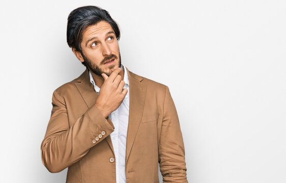 Young hispanic man wearing business clothes thinking worried about a question, concerned and nervous with hand on chin