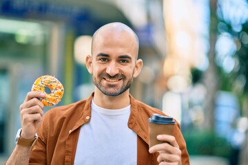 Young hispanic bald man smiling happy having breakfast at the city.