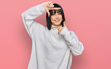 Young brunette woman with bangs wearing casual turtleneck sweater smiling making frame with hands and fingers with happy face. creativity and photography concept.
