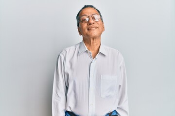 Middle age indian man wearing casual clothes and glasses relaxed with serious expression on face....