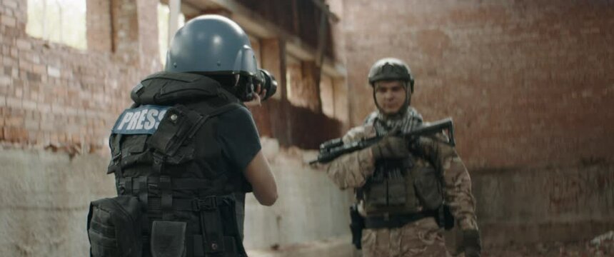 A soldier is posing for female war journalist inside destroyed building. Shot with 2x anamorphic lens