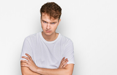 Young caucasian man wearing casual white t shirt skeptic and nervous, disapproving expression on face with crossed arms. negative person.