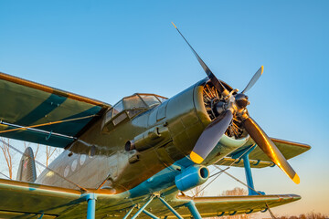 an old passenger military aircraft with a propeller and blades, from the time of the Second World War, stands in the airfield clearing against the blue sky