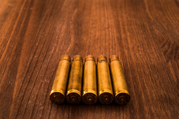 Empty shells from the rifle lie in a row on a wooden table. Focus on the tip of the sleeve