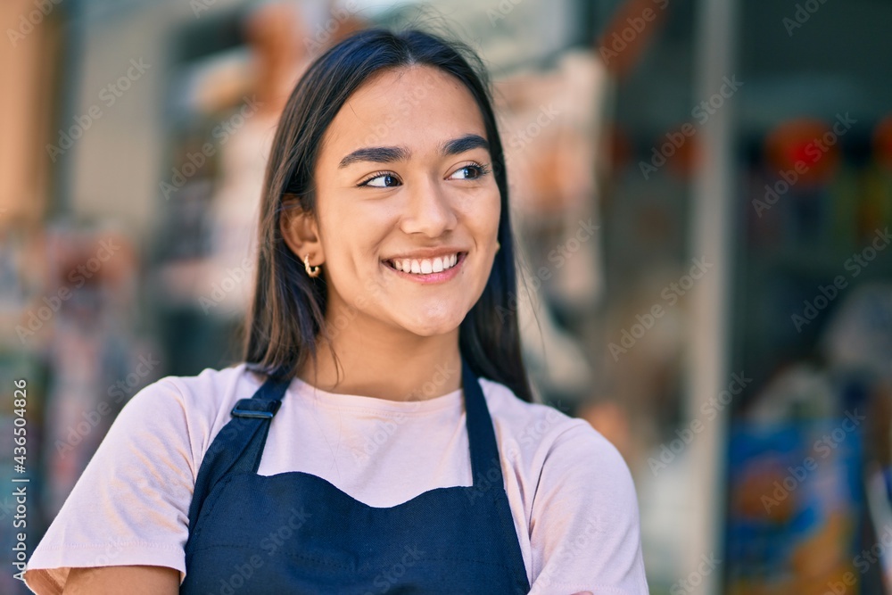 Poster young latin shopkeeper girl smiling happy standing at the press shop