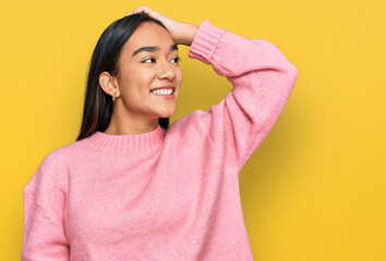 Young asian woman wearing casual winter sweater smiling confident touching hair with hand up gesture, posing attractive and fashionable