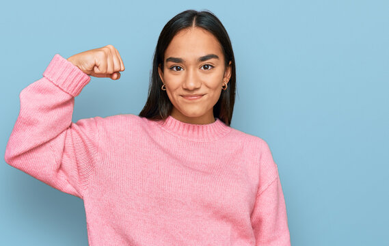 Young asian woman wearing casual winter sweater strong person showing arm muscle, confident and proud of power