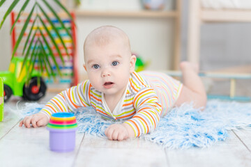 baby boy among the toys in the children's room, cute funny smiling little baby playing on the floor, the concept of children's development and games