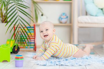 baby boy among the toys in the children's room, cute funny smiling little baby playing on the floor, the concept of children's development and games