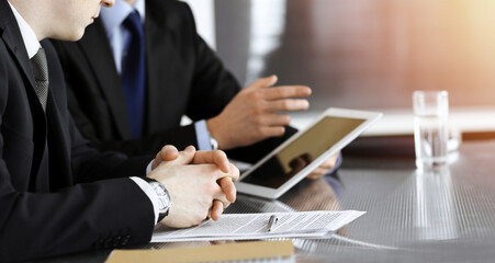 Businessman using tablet computer and work together with his colleague in sunny modern office, close-up. Unknown business people at meeting. Teamwork and partnership concept