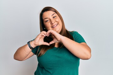 Beautiful brunette plus size woman wearing casual clothes smiling in love doing heart symbol shape with hands. romantic concept.